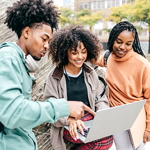 three students looking at a laptop